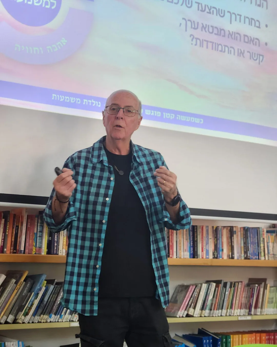 בני סולומון מרצה בערב קהילתי בספרייה, חולצה משובצת, ידיים בתנועה